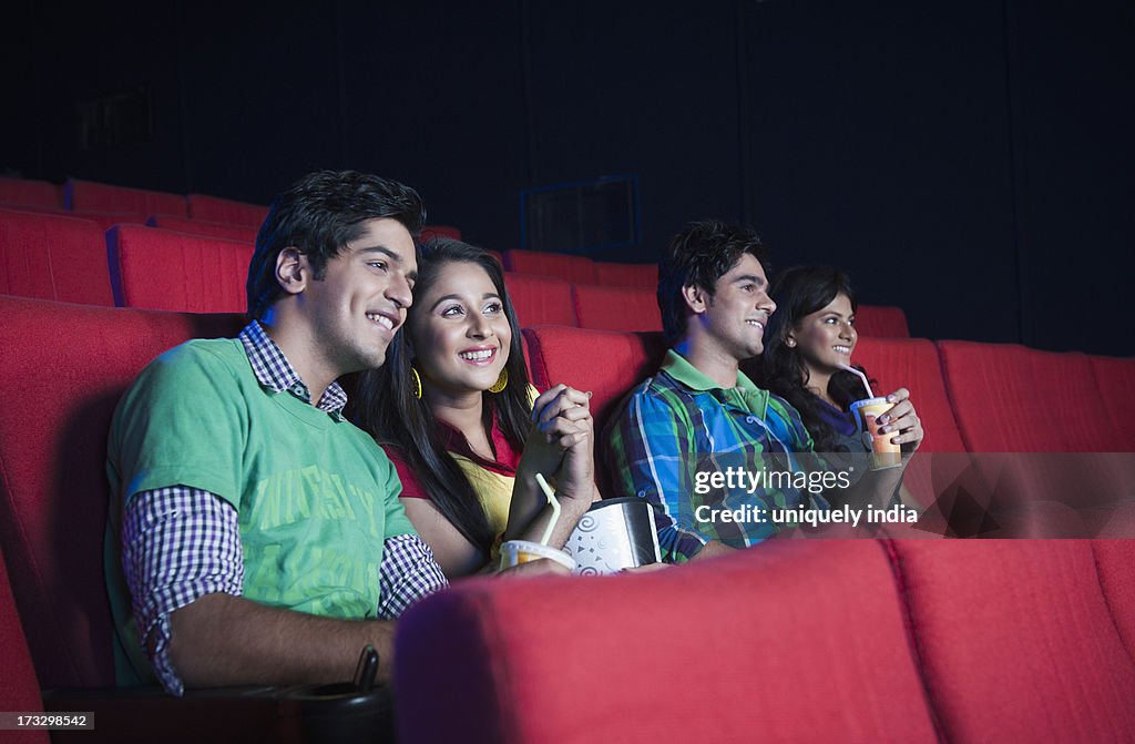 Couple enjoying soft drinks while watching movie in a cinema hall