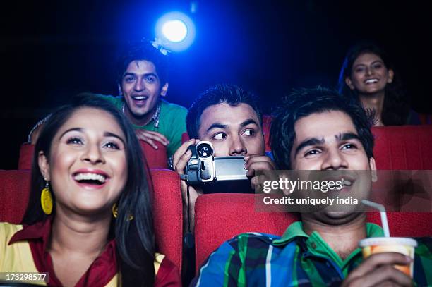 man using video recorder in a cinema hall - indian couple in theaters - fotografias e filmes do acervo