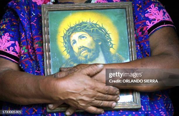 An indigenous women embraces an image of Jesus while she waits for the corpse of one of the victims of a landslide that struck the small town of El...
