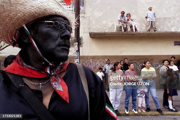 Man, with his face painted in black and dressed like a Mexican Indigenous soldier, looks at the reenactment of the Battle of Puebla 05 May 2001, in...