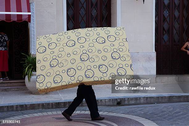 a man carrying a mattress - materasso foto e immagini stock