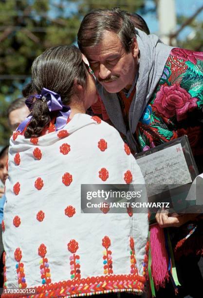 Mexican President Vicente Fox receives a kiss from Juana Garcia Palomar, a Tzotzil Maya craftswoman dressed in costume from Chenalho, while at the...