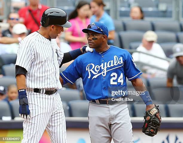 Miguel Tejada of the Kansas City Royals talks with Derek Jeter of the New York Yankees after Jeter is on third base in the first inning on...