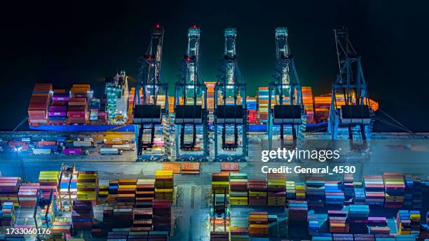 aerial view cargo freight ship working crane in shipyard at night time. - air cargo night stock pictures, royalty-free photos & images
