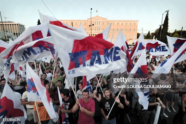 Communist affilited protesters wave flags as they participate in the PAME union rally at Syntagma Square in central Athens on July 11, 2013. Greece's...