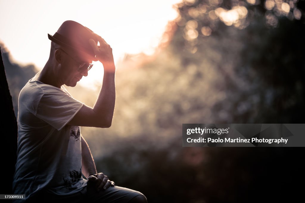 Man with hat and sunglasses at sunset