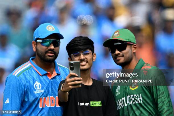 Fan takes a picture with Bangladesh's captain Najmul Hossain Shanto and India's captain Rohit Sharma before the toss at the start of the 2023 ICC...