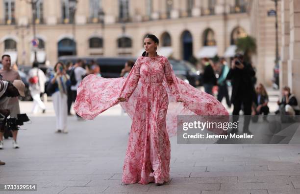 Dy Miryan seen wearing a pink/rose maxidress with floral print, a matching cape and red huge diamond earrings, outside the Giambattista Valli Show...