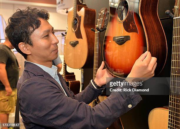 Yoshihiko Tanbara of Yamaha Corporation of America inspects guitars at NAMM's summer event at Music City Centeron July 11, 2013 in Nashville,...