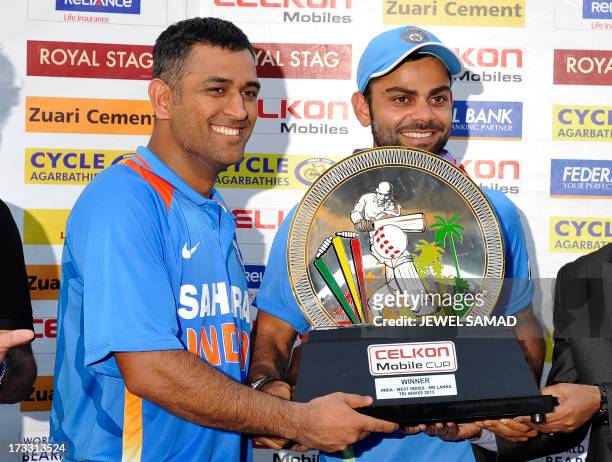 Indian cricket team captain Mahendra Sing Dhoni and teammate Virat Kohli hold their winner trophy at the end of the final match of the Tri-Nation...