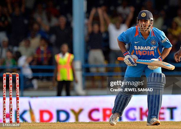 Indian cricket team captain Mahendra Sing Dhoni looks on after hitting a boundary for six runs to seal their victory during the final match of the...