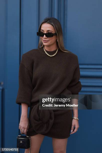 Guest seen wearing Chanel bag, brown knit pullover and matching knit skirt with huge flower detail, brown sunglasses and golden jewelry, outside the...