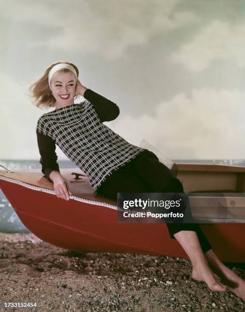 Posed studio portrait of a female fashion model wearing a knitted monochrome crimplene sweater with cross-hatch pattern and black capri pants, she...