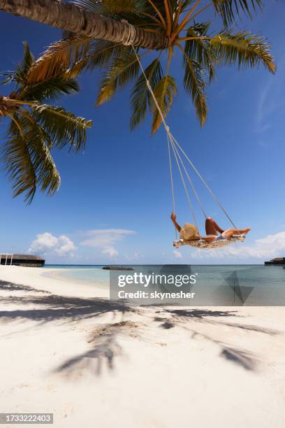 unbeschwerte frau, die sich in einer schaukel am strand entspannt. - indian ocean stock-fotos und bilder