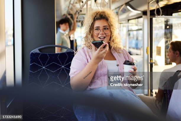 happy overweight woman talking on cell phone's speaker in a bus. - dictaphone stock pictures, royalty-free photos & images