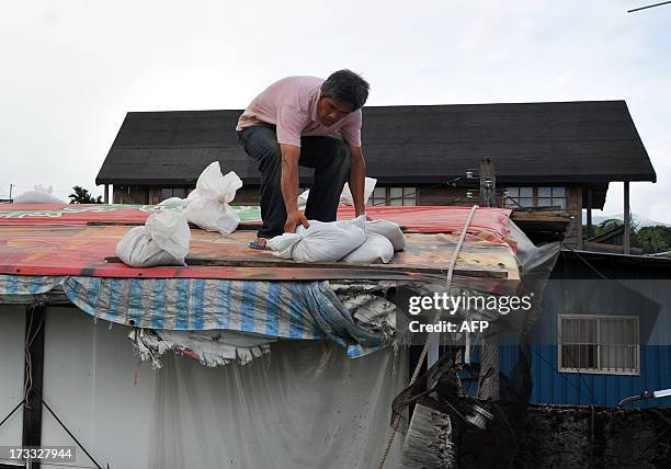 Resident moves stacks of sand bags on a roof to hold back flood waters as typhoon Soulik approaches northern Taiwan in New Taipei City on July 12,...