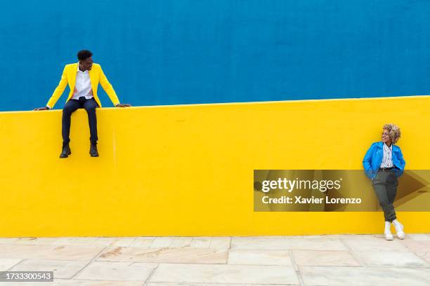 two young african friends keeping social distance over yellow and blue background. friendship and social relationship concept. copy space for text. banner template - man blue background - fotografias e filmes do acervo