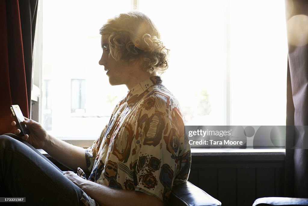 Man sitting on sofa texting on mobile