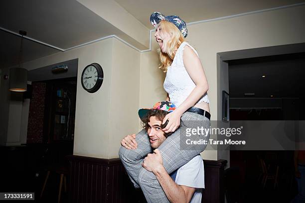 man with woman on shoulders having fun - nur erwachsene stock-fotos und bilder