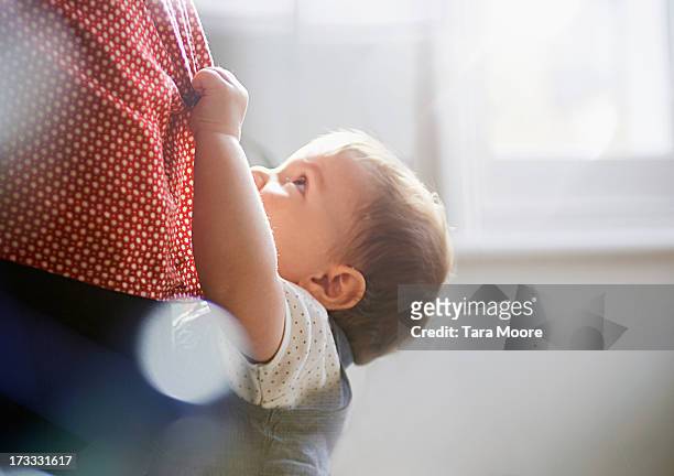 toddler hanging on to mother's dress - baby clothing stock pictures, royalty-free photos & images