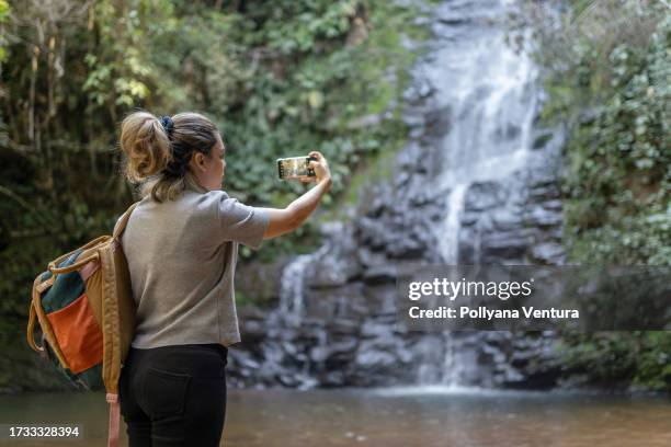 woman taking photo of waterfall - cachoeira stock pictures, royalty-free photos & images