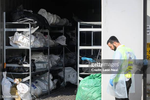 Forensic staff look on as a refrigerated container holding the bodies of Israeli citizens killed during the recent attacks by Hamas is opened, during...