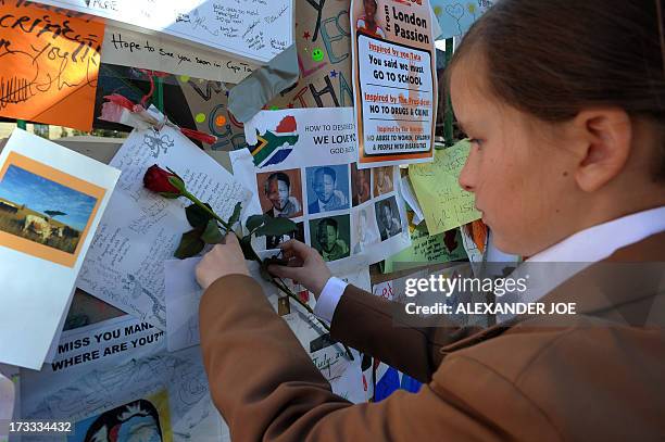 One of 370 school children from Johannesburg sticks a rose among messages and flowers left for former South African President Nelson Mandela on July...