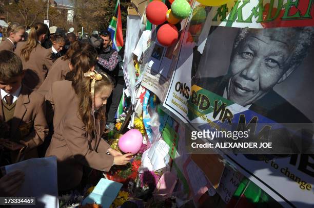 One of 370 school children from Johannesburg sticks a rose among messages and flowers left for former South African President Nelson Mandela on July...