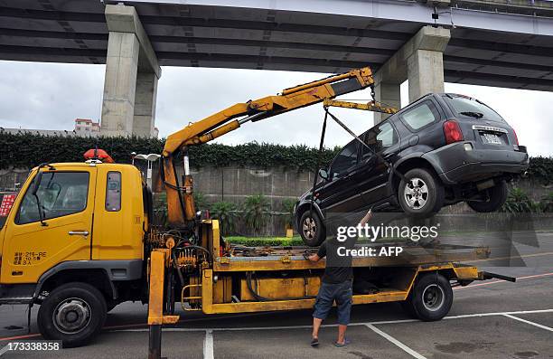 Taipei City Government engineering staff tows a vehicle from Riverside Park in New Taipei City on July 12, 2013. Hundreds of villagers were...