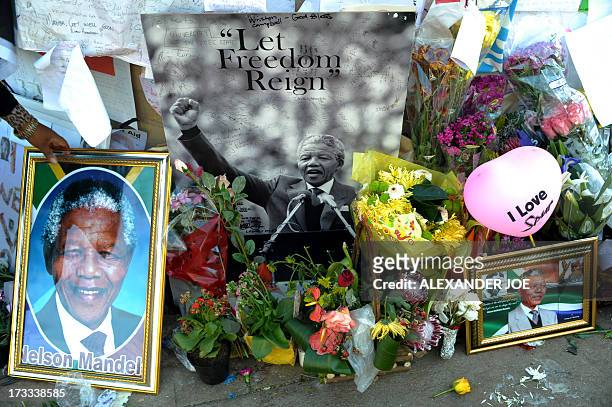 Pictures, messages, and flowers are left by children for former South African President Nelson Mandela on July 12, 2013 outside the MediClinic Heart...