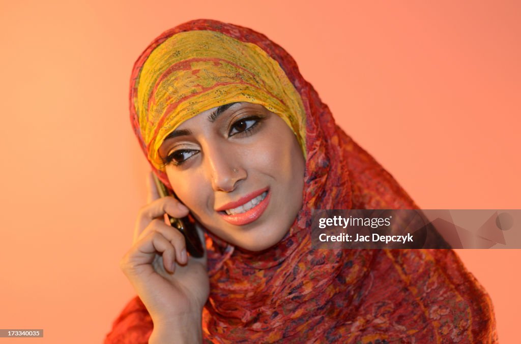 Young woman in hijab speaking on mobile smiling