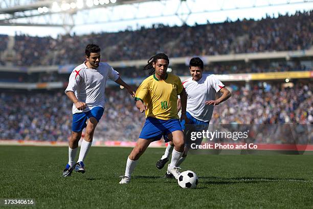 three men playing soccer in stadium - dribbling sports stock-fotos und bilder