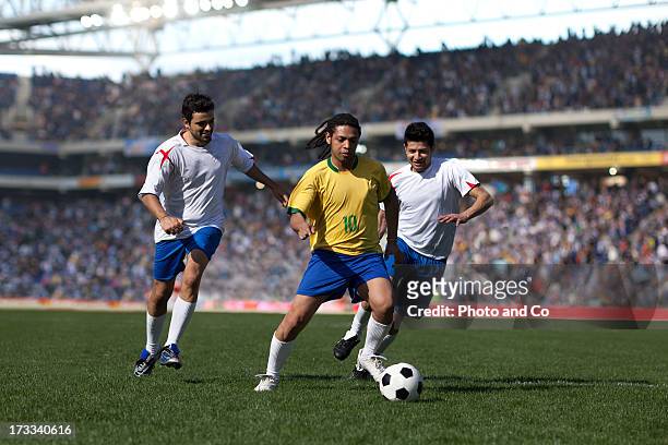 three men playing soccer in stadium - dribbling sports imagens e fotografias de stock
