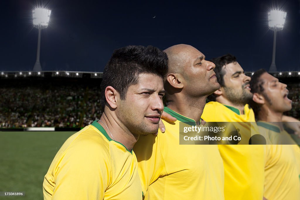 Soccer players singing national anthem in stadium