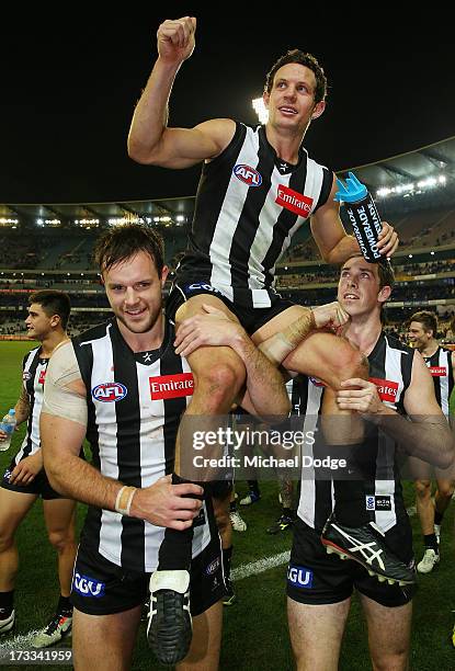 Luke Ball of the Magpies gets carried off after his 200th game by Nathan Brown and Nick Maxwell during the round 16 AFL match between the Collingwood...