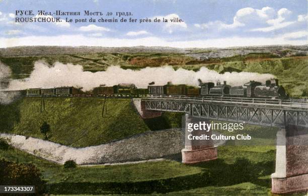 Railway bridge near Ruse, Bulgaria . C. 1900. Steam engine pulling passenger carriages and goods carriages.