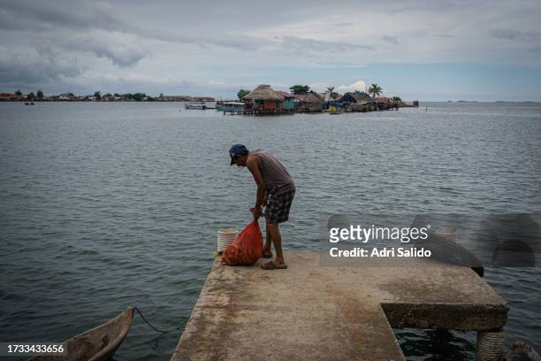 Man unloads a sack of bananas at one of the community's docks on October 11, 2023 in Gardi Sugdub, Panama. Indigenous communities of the small...