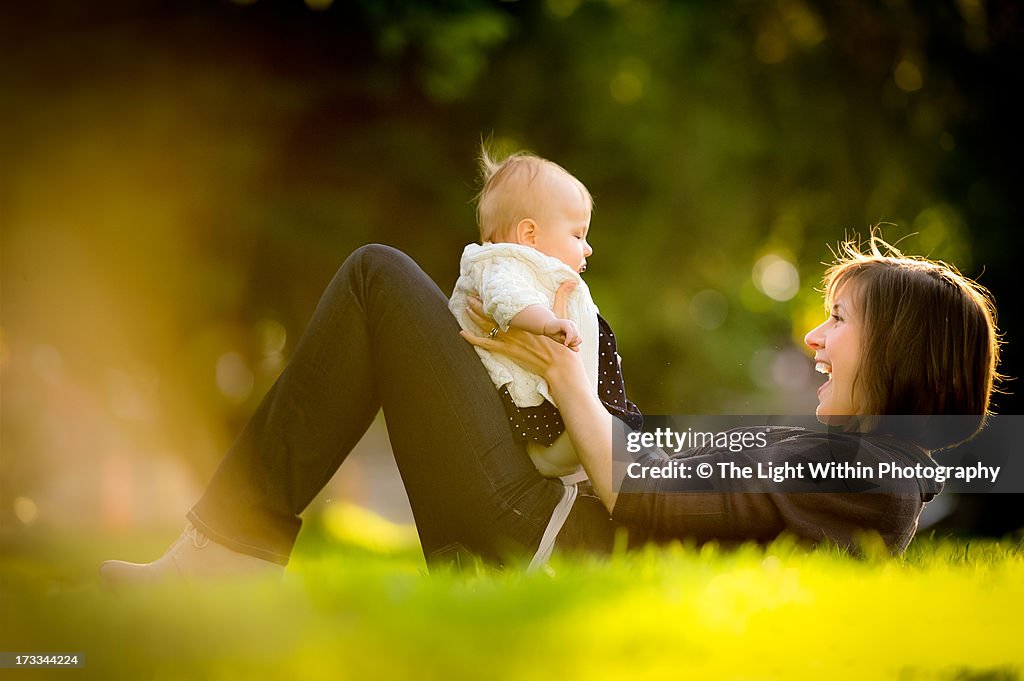 Mother and baby girl play on the grass