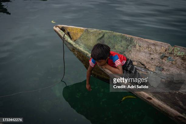 Child sitting on a barche watches and plays with the water on October 11, 2023 in Gardi Sugdub, Panama. Indigenous communities of the small island,...