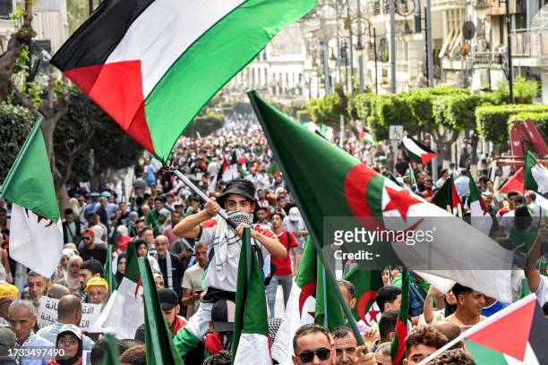 Demonstrators wave Palestinian and Algerian national flags as they march in a rally in solidarity with Palestinians in Gaza in Algiers on October 19,...