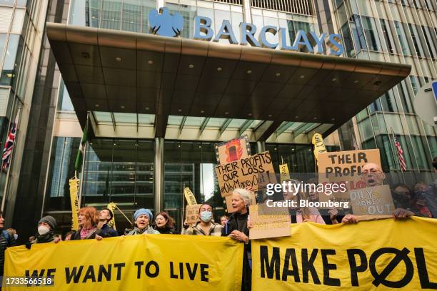 Climate activists hold banners and chant during a protest outside the headquarters of Barclays Plc in Canary Wharf in London, UK, on Thursday, Oct....