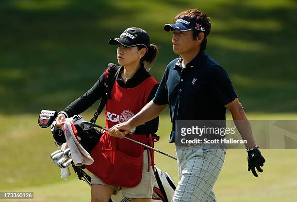 Joe Ozaki of Japan walks alongside his caddie Yasuko Moore on the tenth hole during the second round of the 2013 U.S. Senior Open Championship at...