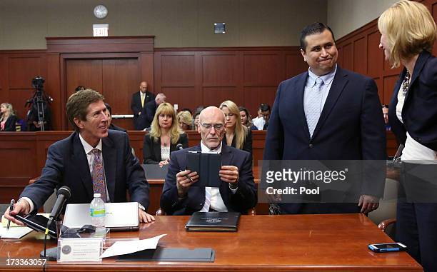 Defendant George Zimmerman smiles while standing with his attorneys Mark O' Mara , Don West and Lorna Truett during his murder trial July 12, 2013 in...