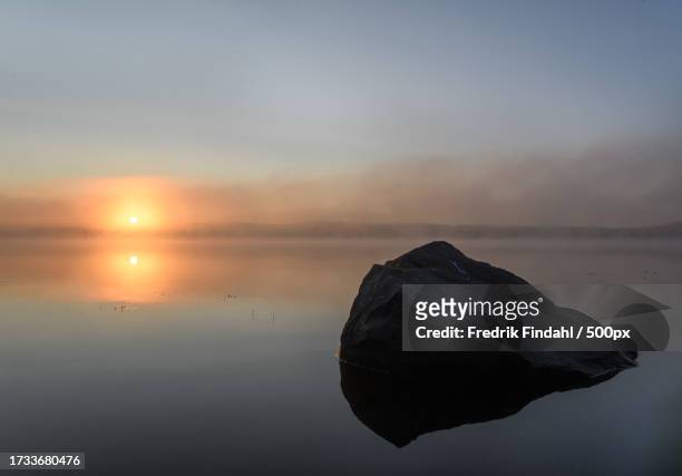 scenic view of rocks in sea against sky during sunset - årstid stock-fotos und bilder