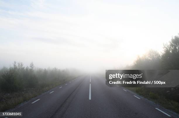 empty road amidst trees against sky - årstid stock pictures, royalty-free photos & images