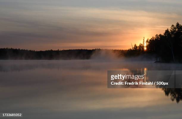 scenic view of lake against sky during sunset - årstid stock-fotos und bilder