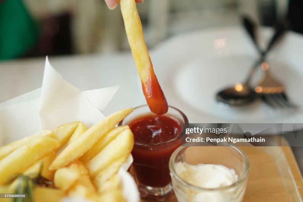 Closeup French fries, Potato chips Yellow crispy fries in wooden basket with tomato sauce and mayonnaise in clear grass, snack delicious food