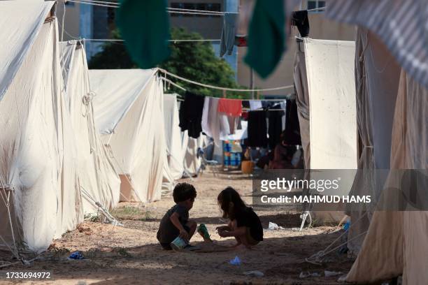 Children play among tents set up for Palestinians seeking refuge on the grounds of a United Nations Relief and Works Agency for Palestine Refugees...