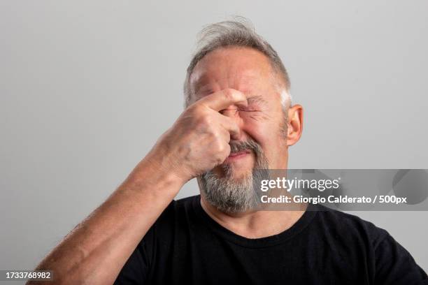 close-up of man screaming against gray background - covering nose stock pictures, royalty-free photos & images