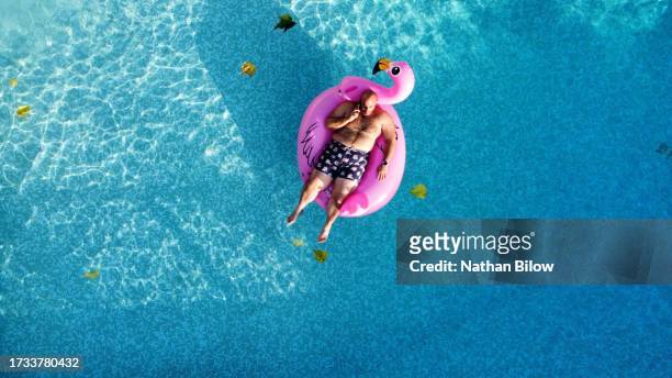 full bodied man floating on pool toy - floating on water stock pictures, royalty-free photos & images